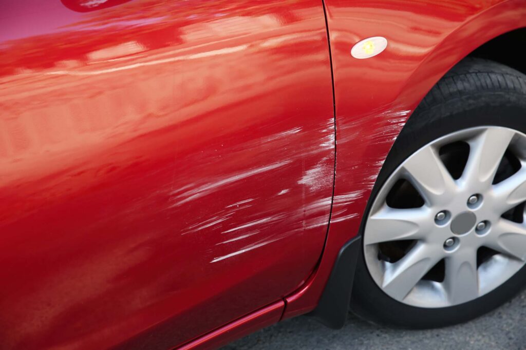 how to remove scratches from car paint - red car with minor scratches on door